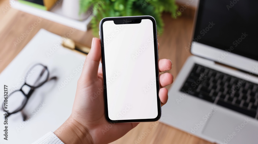 A close up of a phone with a plant and desk in the background. In front of a keyboard. Blank white screen mobile device. Insert your own screen mockup. For app marketing. Nothing on the screen. A close up of a phone with a plant and desk in the background. In front of a keyboard. Blank white screen mobile device. Insert your own screen mockup. For app marketing. Nothing on the screen.