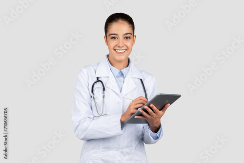 A cheerful female doctor with a stethoscope holds a digital tablet, embodying the intersection