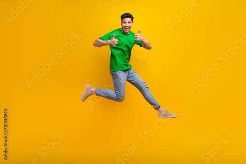 Full size photo of satisfied nice guy wear stylish t-shirt run to empty space showing thumbs up isolated on yellow color background