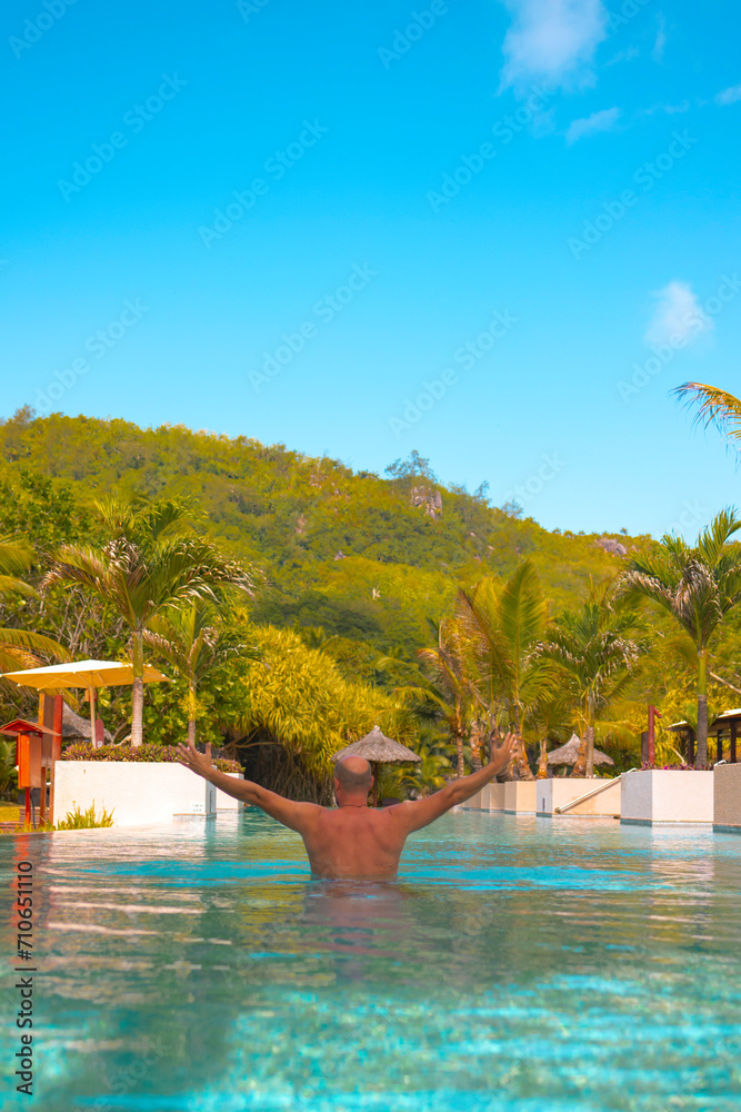happy man swims in a pool in the Seychelles, the concept of a summer vacation