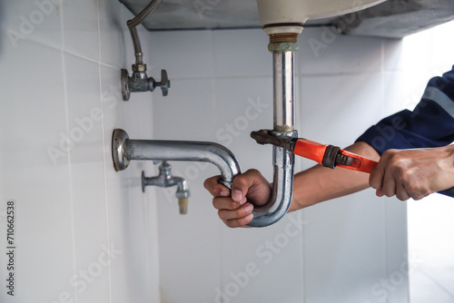 Plumber working in the bathroom, plumbing repair service, repairing leaking sinks with adjustable wrench, assemble and install concept.