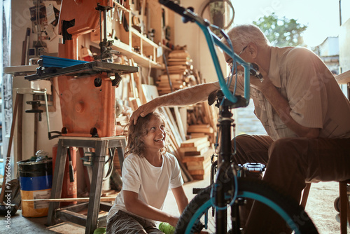Grandfather and grandson fixing a bike in the garage photo