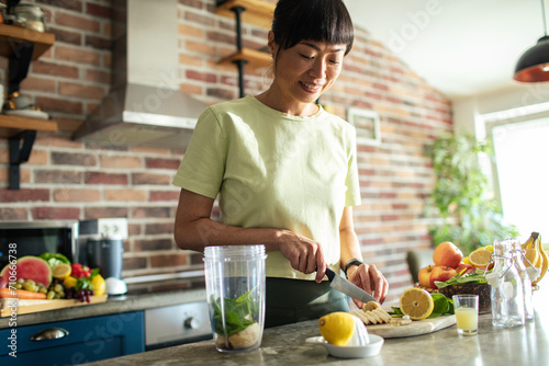 Young asian woman preparing healthy smoothie in home kitchen