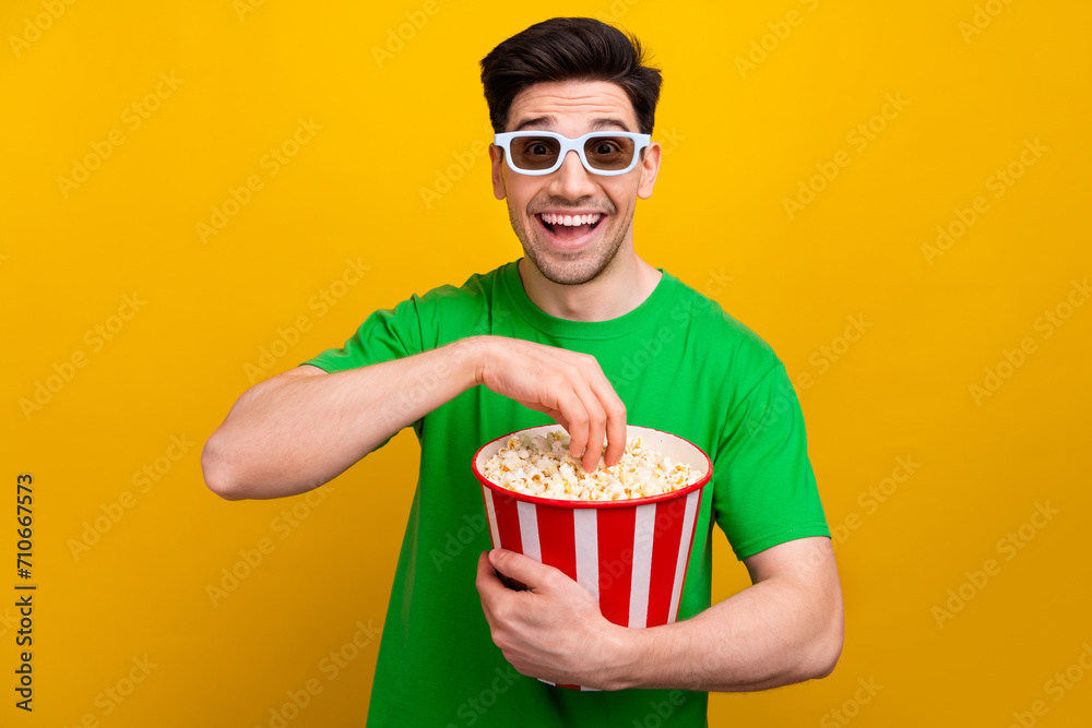Photo of optimistic man with stylish haircut dressed t-shirt 3d glasses eating popcorn at cinema isolated on yellow color background