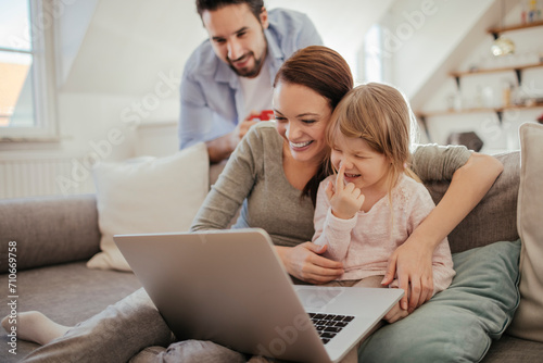 Happy family with young child using laptop on sofa at home © Geber86