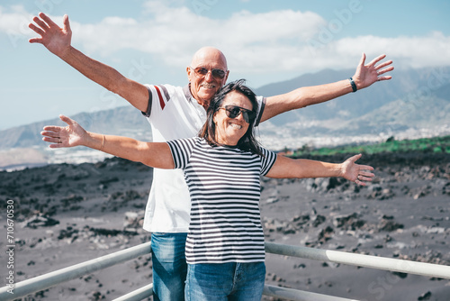 Happy Couple of Senior Caucasian People Standing Outstretched Arms Enjoying Sea Vacation Travel and Freedom. Retirement Lifestyle Concept