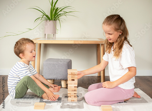 Little boy and girl playing with wooden tower at home, early education, brother and sister