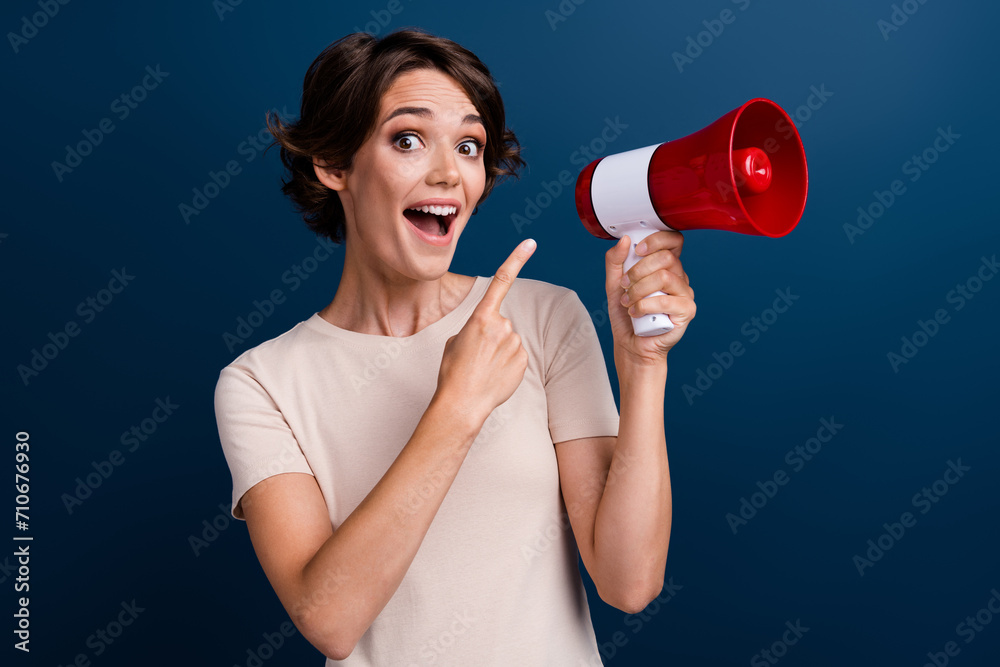 Photo portrait of pretty young girl point excited megaphone wear trendy white outfit isolated on dark blue color background Photo portrait of pretty young girl point excited megaphone wear trendy white outfit isolated on dark blue color background