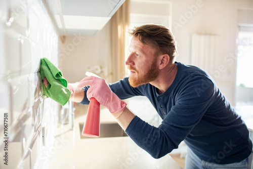 Young man cleaning kitchen tiles at home photo
