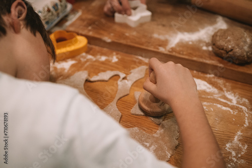 Christmas and New Year celebration traditions. Traditional festive food making, family culinary. Woman cutting cookies of raw gingerbread dough. High quality photo