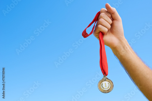 Gold medal, blue sky and hands of sports person winning award, competition victory or game contest. Race champion, challenge winner and closeup athlete with mockup space, success or prize achievement