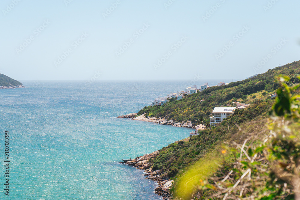 View of Pontal do Atalaia from a hill at Arraial do Cabo, a few houses on the coast behind a mountain.