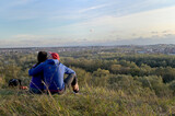 A young couple in love are kissing sitting on a hill near the city
​