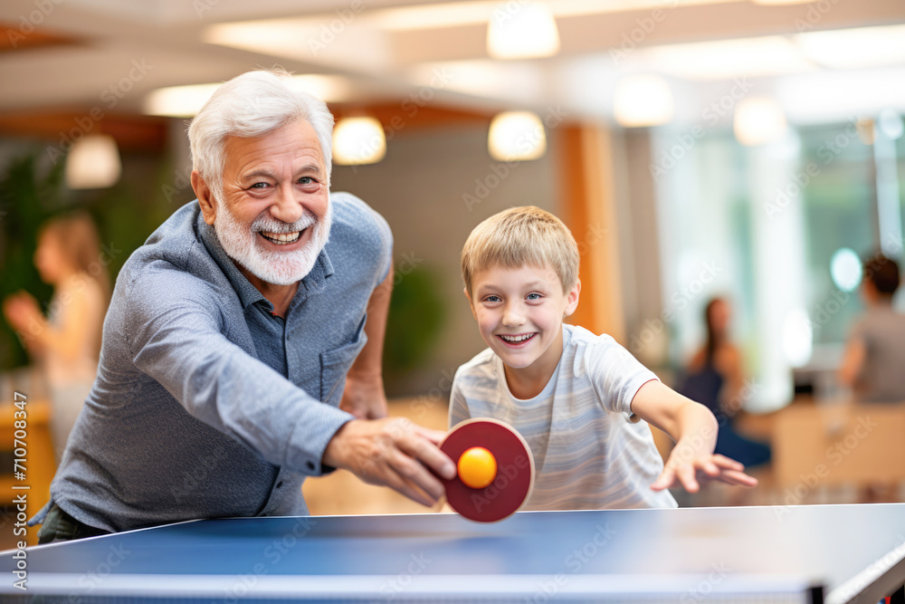 Fototapeta premium A joyful scene of a grandfather teaching his grandson the art of table tennis, creating a fun and recreational family moment.