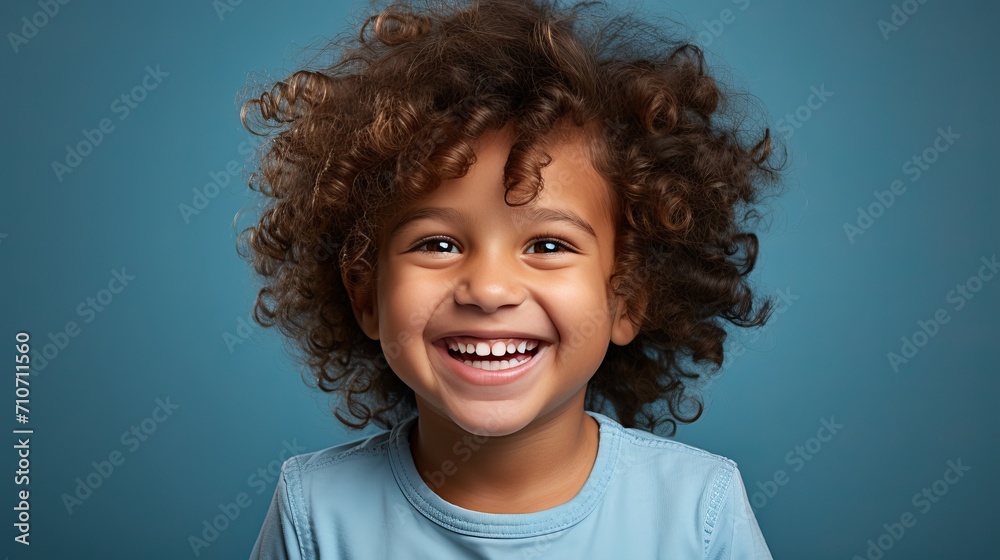 Smiling american boy child model with perfect teeth laughing and posing on blue background Smiling american boy child model with perfect teeth laughing and posing on blue background