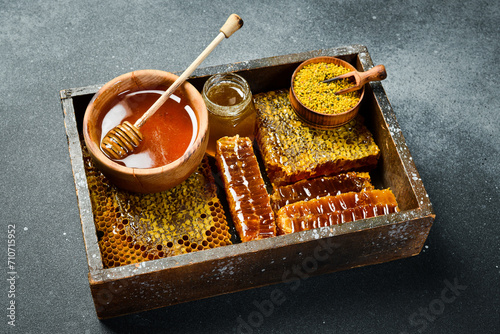 Set of honey, bee products and honeycomb honey. On a dark background. Top view. In a wooden box.