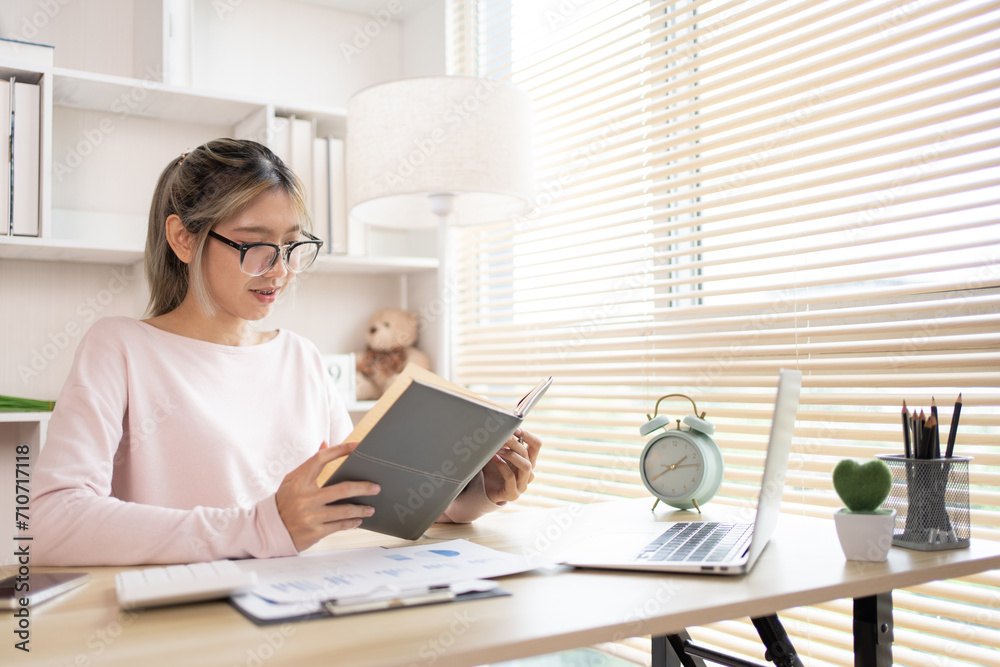 Woman reading book, Student reading a book in a private office, Self study, Textbooks from books, Find out more, In the office there is a computer or laptop placed on the table, Study. Woman reading book, Student reading a book in a private office, Self study, Textbooks from books, Find out more, In the office there is a computer or laptop placed on the table, Study.