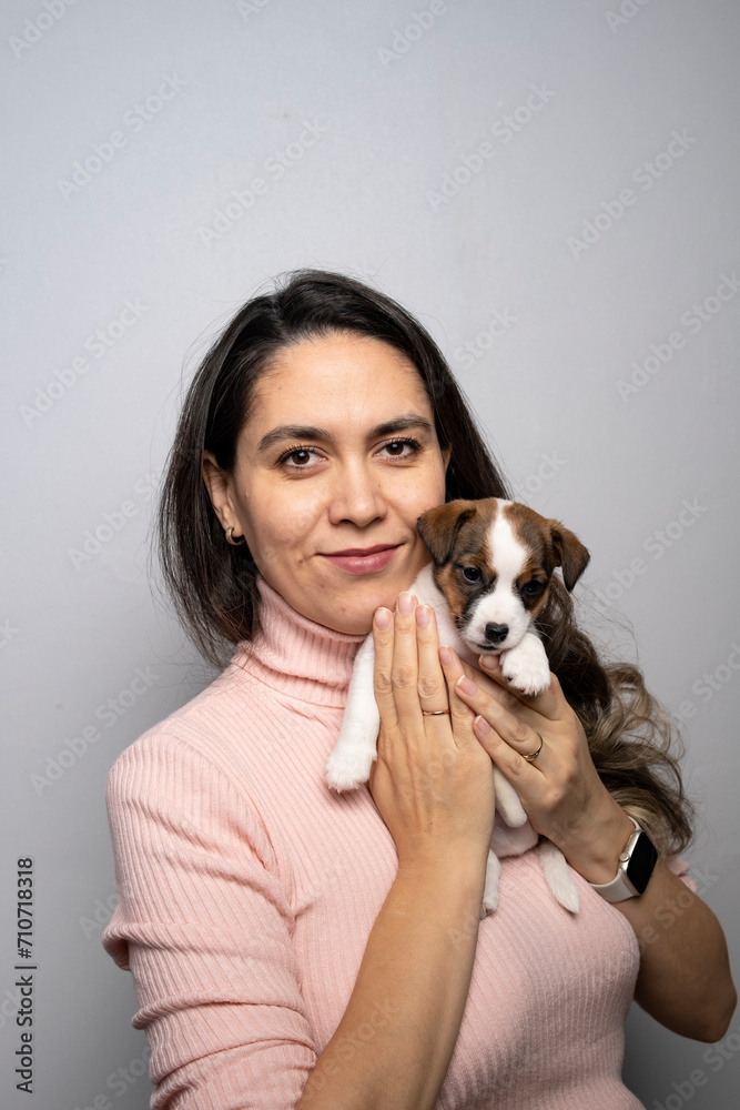 A young girl holds a Jack Russell terrier puppy in her arms. Happy woman with a puppy.