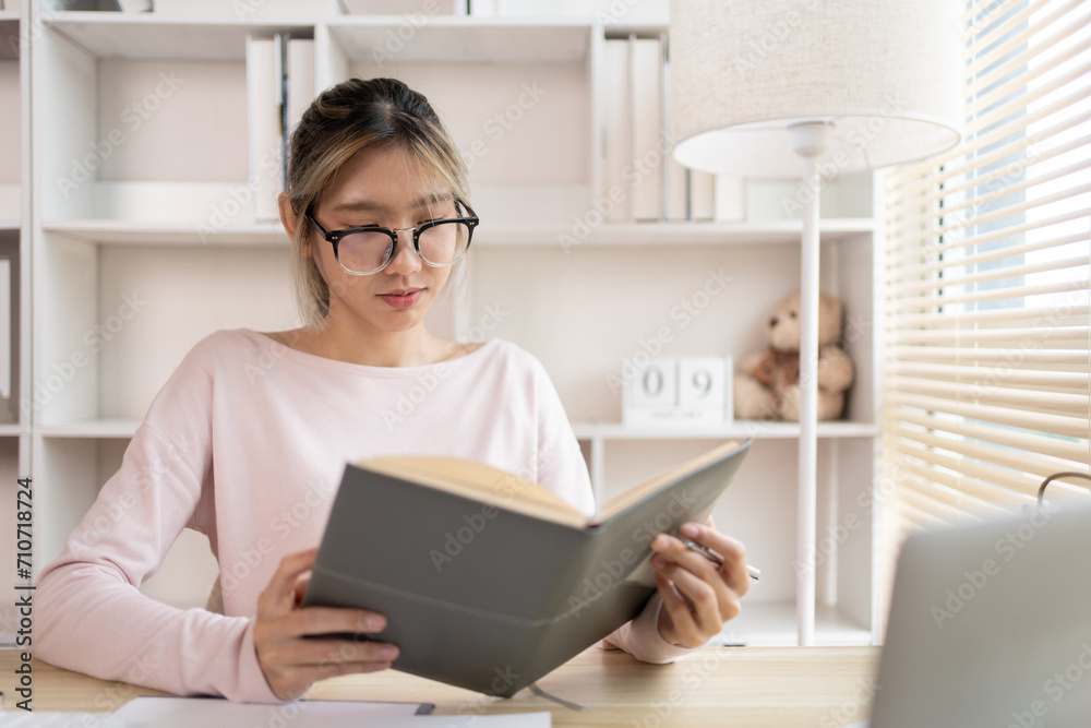 Woman reading book, Student reading a book in a private office, Self study, Textbooks from books, Find out more, In the office there is a computer or laptop placed on the table, Study. Woman reading book, Student reading a book in a private office, Self study, Textbooks from books, Find out more, In the office there is a computer or laptop placed on the table, Study.