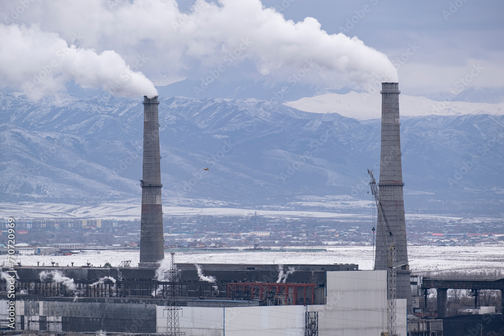 combined heat and power plant, large pipes emitting smoke and harmful substances against the background of a city not far from Almaty. combined heat and power plant, large pipes emitting smoke and harmful substances against the background of a city not far from Almaty.