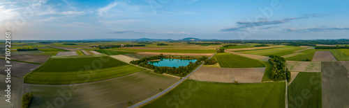 Aerial panoramic view of fields and a pond as the sun sets in late summer under a blue sky with mountains in the distance, Wagram an der Donau, Lower Austria, Austria. photo