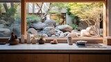  a window with a view of a rock garden and a tea pot on a table with a tea pot in front of it.