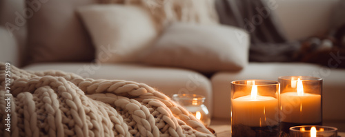 A beige chunky knit blanket on a gray sofa. Coffee table with candles next to the fireplace. Scandinavian farmhouses 