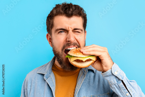 Portrait Of Young Bearded Man Biting Big Tasty Burger  Studio