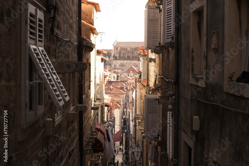 A bustling narrow street winds through the historic limestone buildings of Dubrovnik  Croatia  lined with red roofs  lanterns.