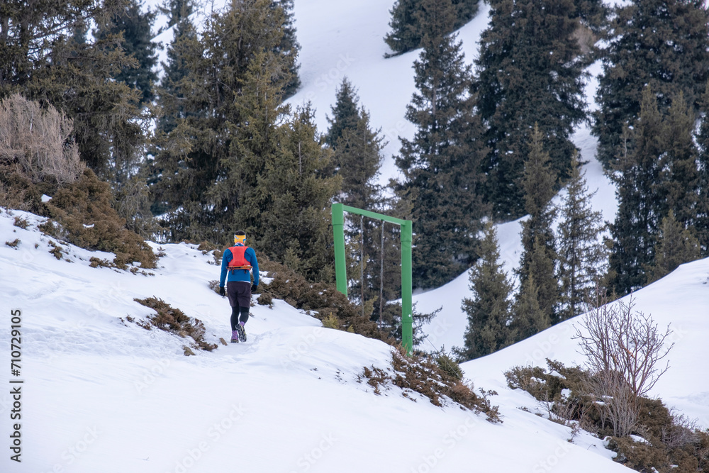 A man in sports gear climbs the snowy slope to the top of the mountain. Ziniy mountaineering is not far from Almaty. Climbing to the top of the winter mountains.