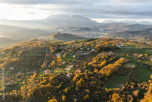 Aerial view of a mountains and hills landscape with vineyard and countryside houses at sunset in autumn colours, Irpinia, Avellino, Campania, Italy.
