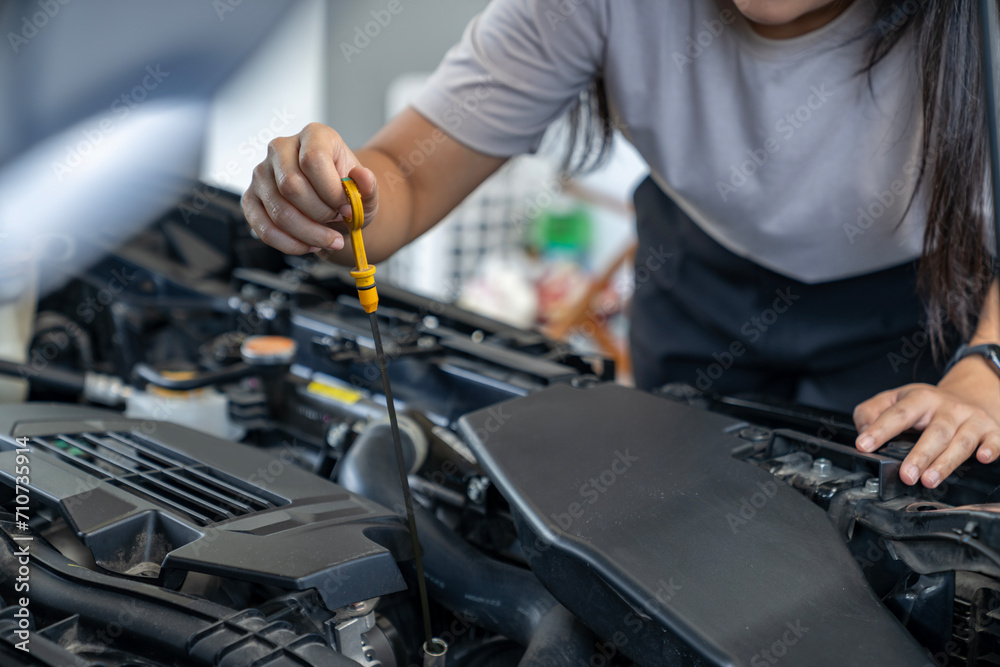 A young woman checking the car engine oil by herself A young woman checking the car engine oil by herself