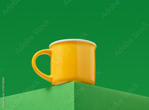 Yellow brightly colored beverage cup on a green background.