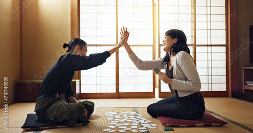 Man, woman and game with cards, high five and challenge on floor, contest or problem solving with clue. People, couple and karuta for competition with paper, reading and celebration for win in home photo