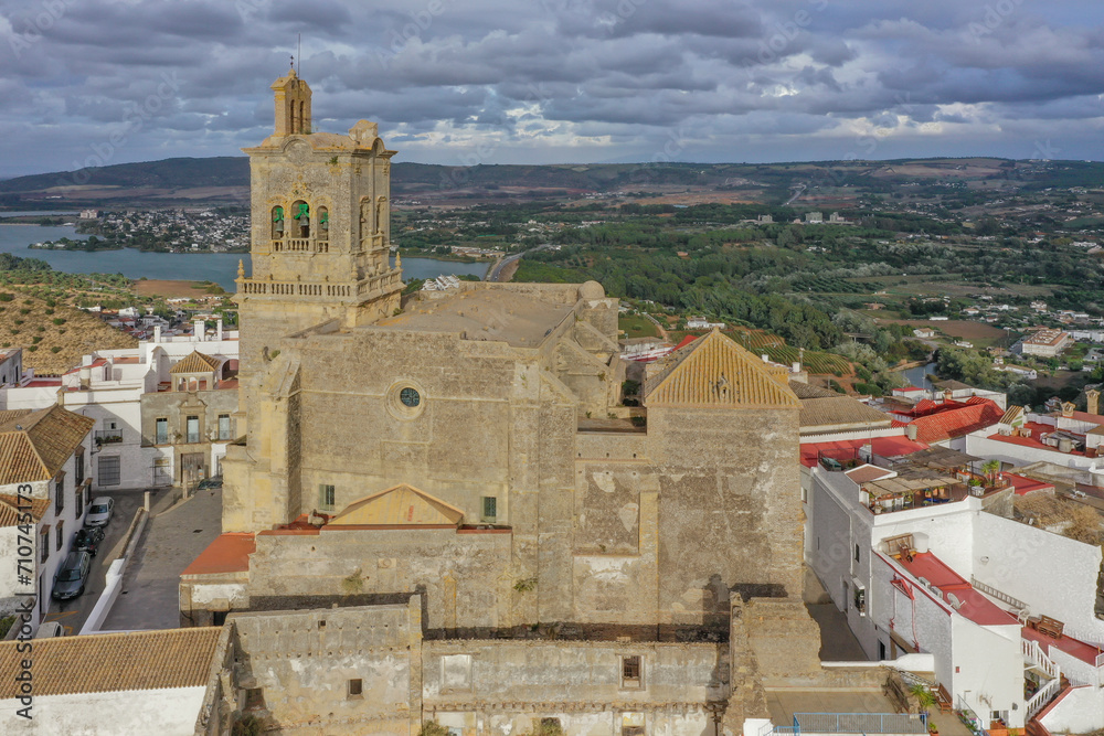 Aerial view of a cathedral, Iglesia de San Pedro atop a sandstone ridge in the town of Arcos de la Frontera in Cadiz, Andalusia, Spain. Aerial view of a cathedral, Iglesia de San Pedro atop a sandstone ridge in the town of Arcos de la Frontera in Cadiz, Andalusia, Spain.