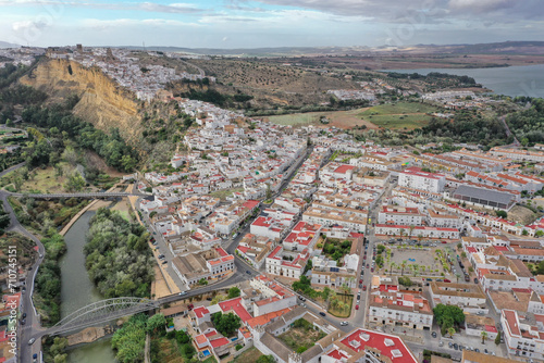 Aerial view of the town of Arcos de la Frontera with a lake in the background and its white houses and red roofs going up towering vertical cliffs in Cadiz, Andalusia, Spain. photo