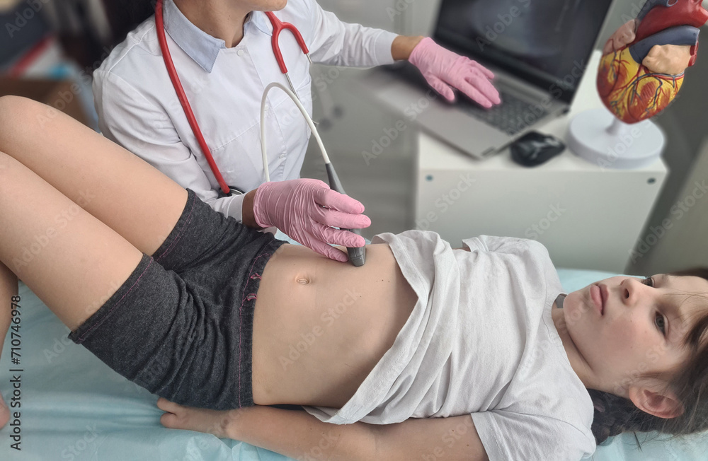 Fototapeta premium Sonographer moves transducer on little girl belly