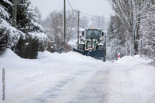 Tractor clears snow on road after heavy snowfall, road maintenance in winter season, harsh weather
