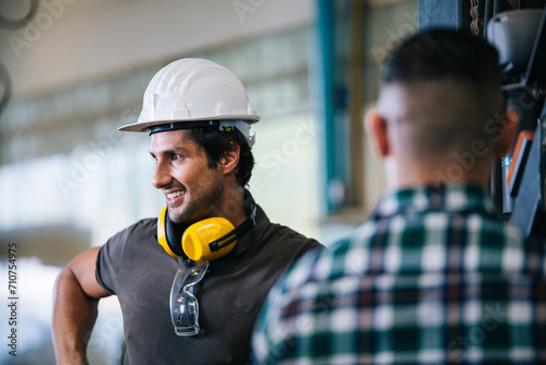 Two engineer or factory technician workers wear hard hat helmet talking about work in industrial manufacturing. Communication with colleagues, teamwork and corporate people concept
