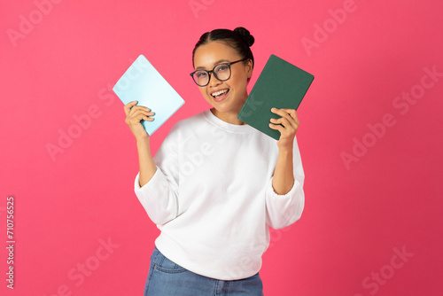 Cheerful asian woman wearing glasses holding books in hands and smiling