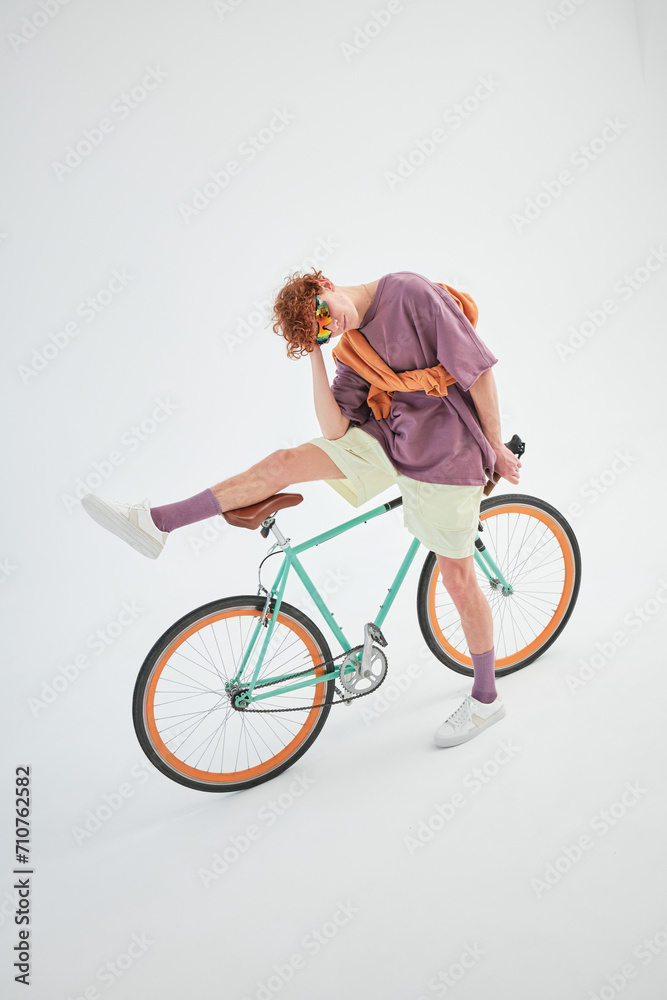 studio portrait of a red-haired young stylish sporty man with a bicycle studio portrait of a red-haired young stylish sporty man with a bicycle