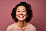 Happy mature Asian woman with dark hair on studio background