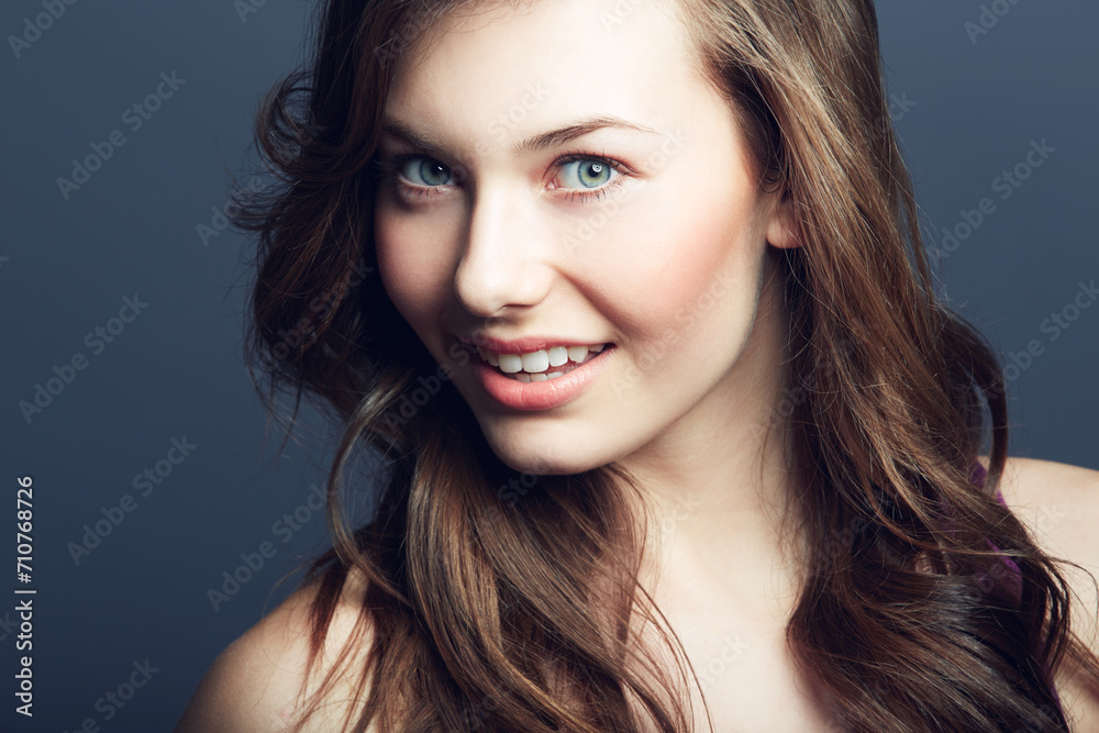 Obraz premium Portrait, natural beauty of woman and hair care in studio isolated on a blue background. Face, hairstyle and cosmetics of happy model at spa for facial treatment, wellness or skin health for glow