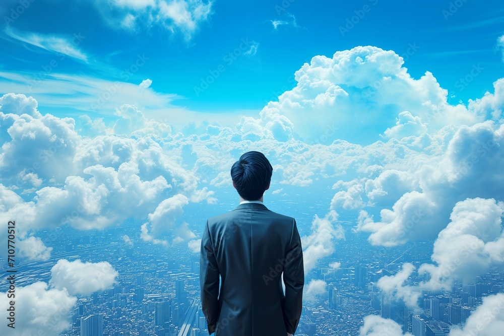 A businessman behind looking for town and blue-sky clouds on building top views. A businessman behind looking for town and blue-sky clouds on building top views.