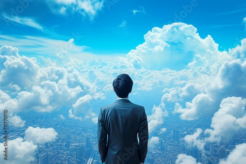 A businessman behind looking for town and blue-sky clouds on building top views.
