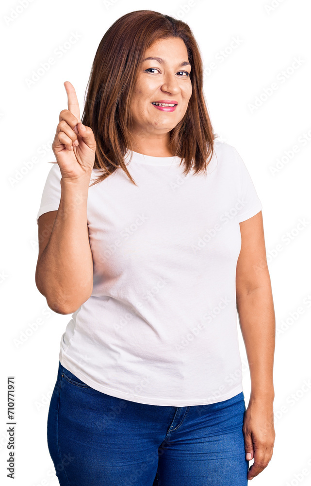 Middle age latin woman wearing casual white tshirt pointing finger up with successful idea. exited and happy. number one. Middle age latin woman wearing casual white tshirt pointing finger up with successful idea. exited and happy. number one.