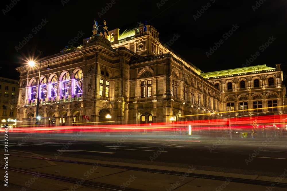 Wiener Staatsoper bei Nacht mit Langzeitbelichtung des Verkehrs im Vordergrund.