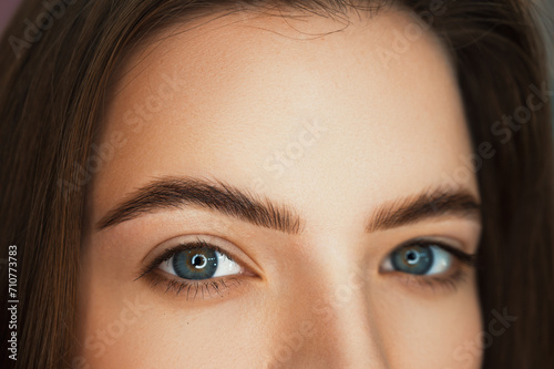 A beautiful girl of model appearance with laminated eyebrows. Close-up of laminated and tinted eyebrows. Eyebrow grooming trend. Lamination and eyelash extensions. High end beauty retouching.