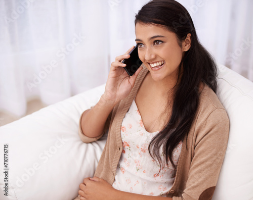 Happy woman on sofa with phone call  relax and communication with mobile connection in apartment. Indian girl sitting on couch with smile  talking on cellphone and discussion for networking in home.