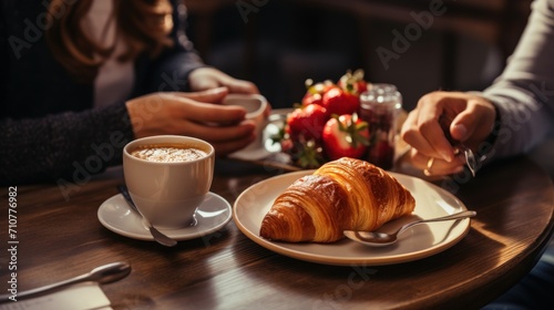  a close up of a plate of food on a table with a cup of coffee and a croissant.
